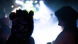 © Travel 'n' Lifestyle - View of two people in silhouette, one wearing a furry animal hat, enjoying a night concert with bright stage lights at the Oregon Country Fair in Veneta, Oregon, United States.