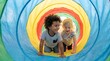© Eka - Two Happy Diverse Children Crawling and Playing in a Colorful Rainbow Toy Tunnel