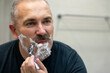© Maria - Middle aged handsome man shaving his beard in bathroom