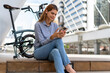© Nassorn - Young Woman with Laptop and Bicycle: A young woman in casual attire sits on steps with her laptop and a cycle beside her, suggesting bike to work and an active lifestyle in an urban setting.