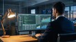 © MubasherHassan - Rear view of businessman working late in corporate office analyzing data charts and software code on large monitor