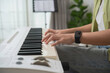 © WMSTUDIO - Person Playing Piano Keyboard at Home with Digital Device on Wrist Watch and Natural Light from Window