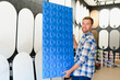 © Serhii - Man holding decorative blue wall panel in decor studio