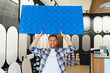 © Serhii - Man holding decorative wall panel in shop