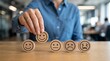 © GRAPHIC - Hand placing a happy face wooden coin for customer service feedback and satisfaction rating