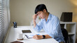 © matinee - Stressed young Asian businessman thinking about a difficult report at his office desk.