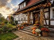 © superstock - Traditionelles deutsches Fachwerkhaus zum Erntedankfest: Eingang und Garten sind festlich mit Kürbissen, Mais, Herbstblumen, Kränzen und Erntegaben dekoriert.