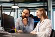 © DC Studio - Jolly system administrator mentors a junior developer at an office desk, teaching coding best practices and guiding the female intern through project tasks at a technology startup.