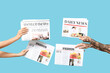 © Pixel-Shot - Female and male hands with newspapers on blue background