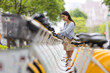 © leungchopan - Woman unlocking public bicycle at urban rental station