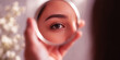 © Hymayun Kabir - Close up of a beautiful young woman looking into a small round mirror reflecting a clear brown eye