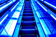 © Takuma Imamura - Futuristic neon blue glowing escalator moving upward in modern Tokyo building, symbolizing progress, career advancement, and technology.