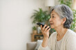 © SmileMemoriesPhoto - Side profile of senior woman speaking to a smartphone in a room with p
