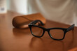© Maxi Perez - Gafas inteligentes de montura negra con cámara integrada y estuche de cuero sobre mesa de madera