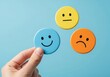 © Sumiya - Hand holding a blue smiley face icon with yellow and orange icons nearby