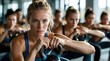 © miss irine - Woman holds kettlebell in gym class. Females in athletic wear workout together, focused on strength training. Group fitness session promotes healthy active lifestyle.