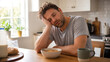 © solom - Tired exhausted man sleeping at kitchen table during breakfast with bowl of cereal and coffee mug feeling sleepy burnout early morning fatigue in cozy home interior