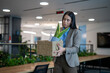 © SISMIZ - Woman carrying a box of personal items leaving her office after being laid off
