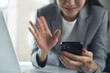 © tippapatt - Asian business woman using smartphone for video call during working with laptop on office desk, modern lifestyle