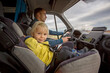 © Tomsickova - Cute toddler boy, kid sitting on the front seat in child seat on big camper van, smiling