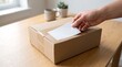 © hamitrap - Hand placing blank label on cardboard box for shipping
