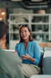 © Zamrznuti tonovi - Asian businesswoman discussing and gesturing, participating in a professional meeting, sharing ideas in a modern office lounge
