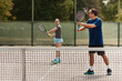 © Nikola Spasenoski - Two players engage in a friendly tennis match on an outdoor court in bright daylight, showcasing their skills and competitive spirit during an afternoon practice session