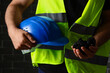 © Pixel-Shot - Construction worker in safety vest holding a blue hard hat and raw coal in hands, energy industry and mining