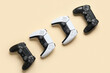 © Pixel-Shot - Four modern video game controllers, two black and two white, arranged diagonally on a light beige background