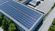 © Generative AI - Aerial view of solar panels installed on the roof of a modern industrial building next to a loading dock with trucks.