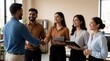 © Maryna - Indian HR team welcomes new male employee with handshake in modern office. Pro recruitment staff smile at job applicant during successful interview. Business people celebrate hiring success, career