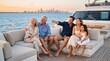 © Ievgeniia - Multi generation family relaxing barefoot on luxury yacht deck at sunset, smiling and pointing toward distant skyline across calm sea, enjoying vacation together
