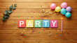 © Tariq - Colorful party signage with balloons and confetti on rustic wooden table top view flat lay with displays colorful square blocks spelling party wooden background balloons