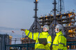 © BESTIMAGE - Team industrial workers training petroleum engineering in oil refinery project operation brainstorm at fuel industry Two male engineers hold laptop and pointing near oil refinery at nighttime