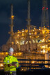 © BESTIMAGE - Industrial worker talk assignment petroleum engineering in oil refinery briefing guidance operation at fuel industry Male engineer holding tablet inspecting near lighted oil refinery at night
