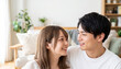 © Jesse_4160 - Happy young Japanese couple smiling and looking at each other in a bright living room at home