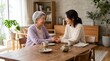 © ALLmost - An elderly woman and a younger woman holding hands across a table, sharing a moment of connection and conversation.