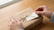 © ArtFocus Studio - Hands tying string around a kraft gift box