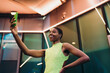© BullRun - Cheerful African American woman capturing selfie video blog on modern smartphone held high. Happy black female influencer posing for social media network feed on architectural background.