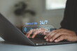 © MUNTHITA - Customer service concept. Businessman using a laptop with contact icons for email, phone and chat, representing 24/7 support, communication, online assistance and business service.