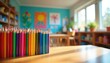 © miss irine - Many sharpened colorful pencils stand on wooden table inside bright elementary classroom. Blurred background shows shelves with books, wall art. School supplies ready for creative art lesson.