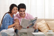© IndiaPix - Young couple reading newspaper together at home