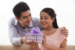 © IndiaPix - Smiling young woman receiving gift from man at home