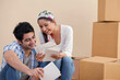 © IndiaPix - Happy young couple looking at photographs together at new home