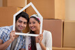 © IndiaPix - Portrait of smiling young couple looking through a house shaped frame