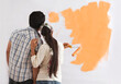 © IndiaPix - Rear view of couple looking at paint sample on the wall