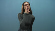 © Krakenimages.com - Woman cupping hand to mouth and shouting in studio, wearing glasses and turtleneck; urgent announcement.