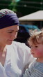 © Marco - Mother embracing toddler during outdoor social gathering, heartwarming family interaction highlighting emotional security, affection, nurturing care and strong parent child bond