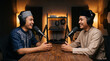 © Guntur - Two Young Muslim Men Laughing Joyfully Facing Each Other During an Interactive Discussion in a Podcast Recording Session
