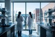 © Vadym - Two women in lab coats stand looking out a large window in a modern research facility. Glassware fills benches with blue liquid. Science and medicine progress.
